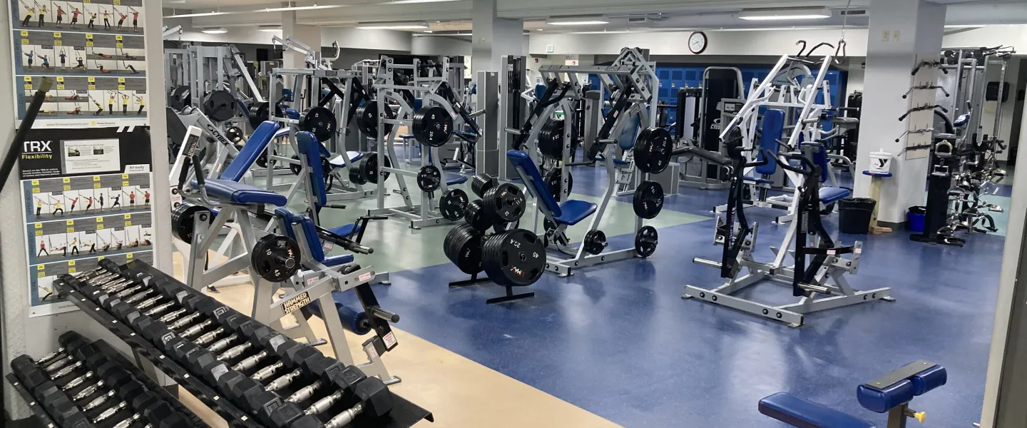Spacious fitness center featuring a variety of exercise machines, free weights, and instructional posters; a great space for wellness programs.
