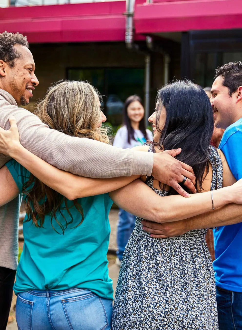 Group of people in a close embrace demonstrating strong community bond during a gathering, possibly supporting the local programs.